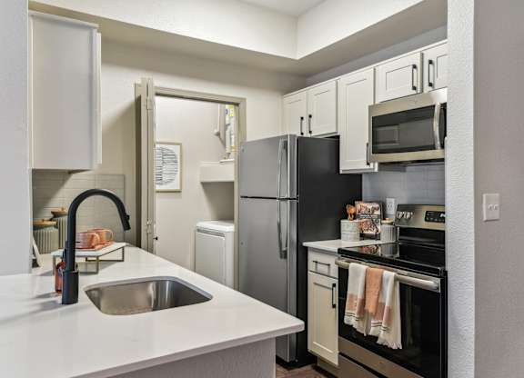 A kitchen with a black refrigerator and white countertops.at Onyx183, Austin, TX  