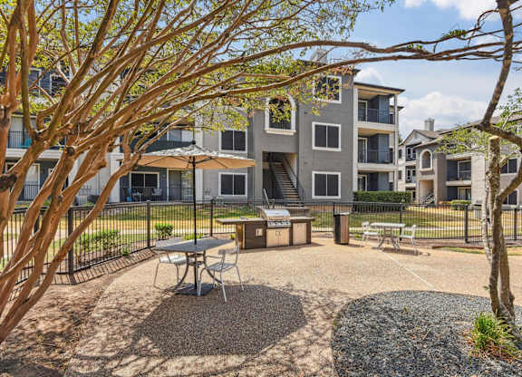 A courtyard with a picnic table surrounded by trees and apartment buildings.at Onyx183, Austin, TX 78729  