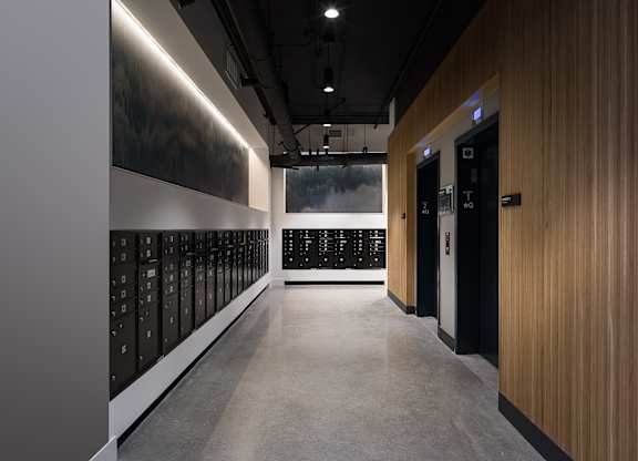 A long hallway with a wall of lockers on the left and a wall of doors on the right.