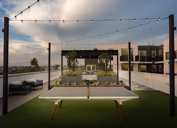 A patio with a table and chairs overlooking a cityscape.