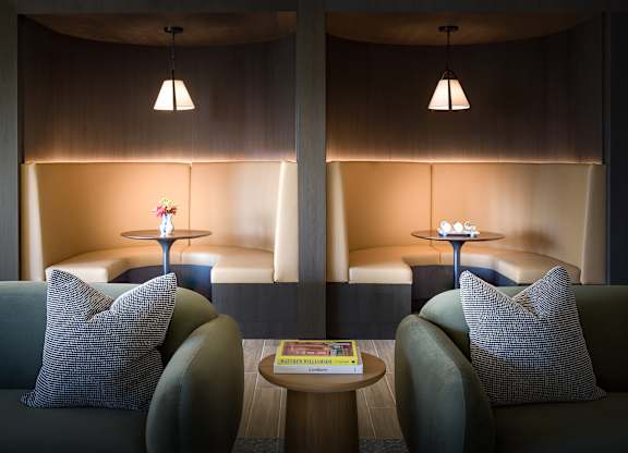 Two green couches in a room with a round table between them.