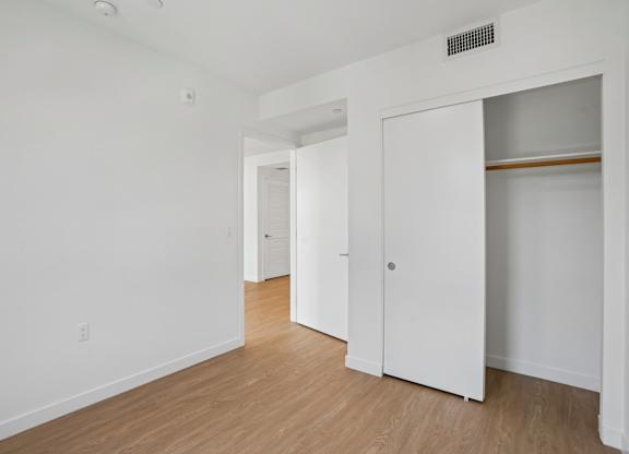A white room with a wooden floor and a white closet.