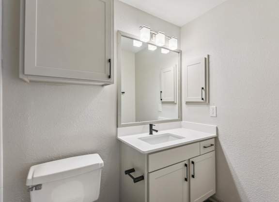 A white bathroom with a toilet, sink, and mirror.at Onyx183, Austin Texas  
