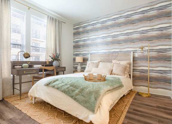 A bedroom with a large bed and a desk with a lamp.at The Vale at the Parks, Washington, DC  