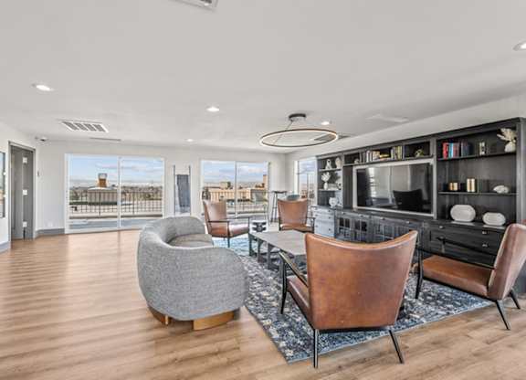 A modern living room with a grey chair and brown leather chairs. at The Lex At Lowry, Denver