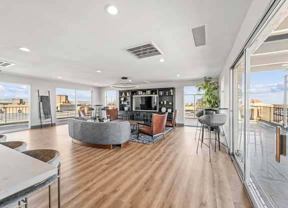 A modern living room with a curved sofa and a television. at The Lex At Lowry, Denver, CO