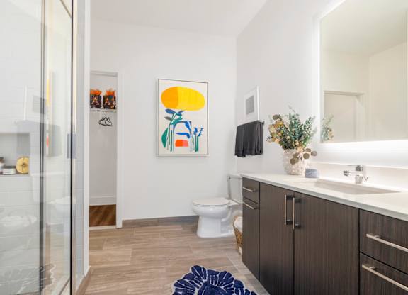 A bathroom with a toilet, sink, and a painting on the wall.at The Vale at the Parks, Washington District of Columbia  