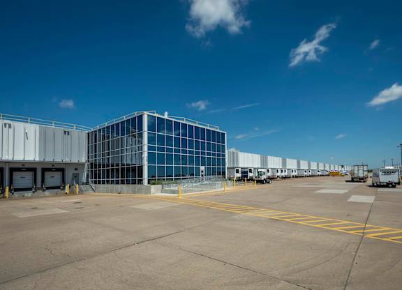 A large building with a glass facade is surrounded by a parking lot.