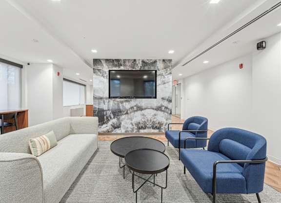 A living room with a grey couch, a blue chair, and a black table at Sherwood at Southern Towers, Alexandria, 22311