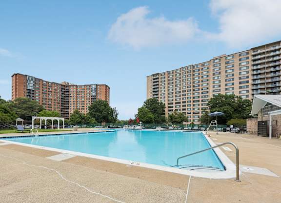 A swimming pool in a sunny day surrounded by buildings.