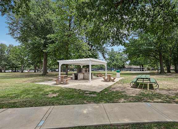 A park with a pavilion, picnic tables, and a green bench.