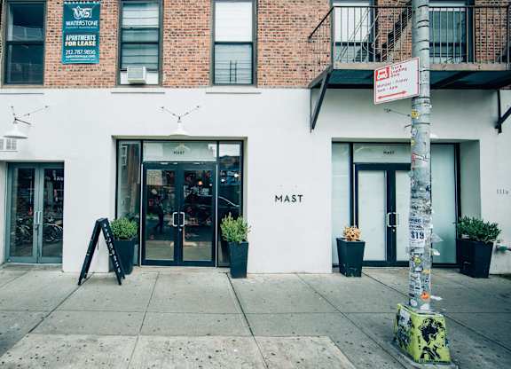 A white building with a black awning and a sign that says "MAST" on it.