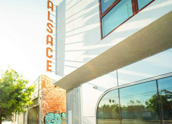 A modern building with a glass facade and a red brick wall with a mural on it.