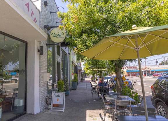 A yellow umbrella is on a table outside of a restaurant.
