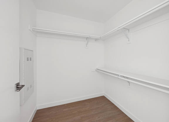 A white room with a door and a shelf.