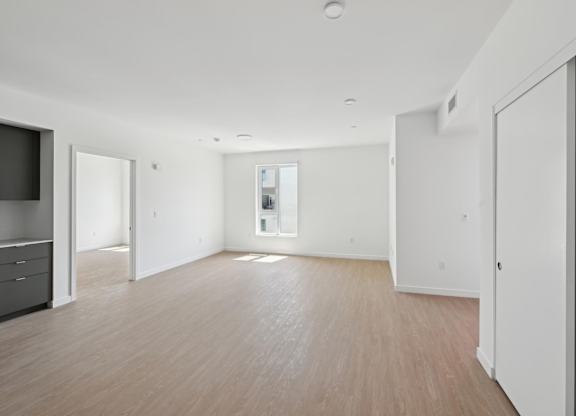 A spacious room with wooden flooring and white walls.