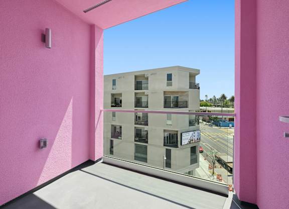 A pink wall with a window overlooking a building.