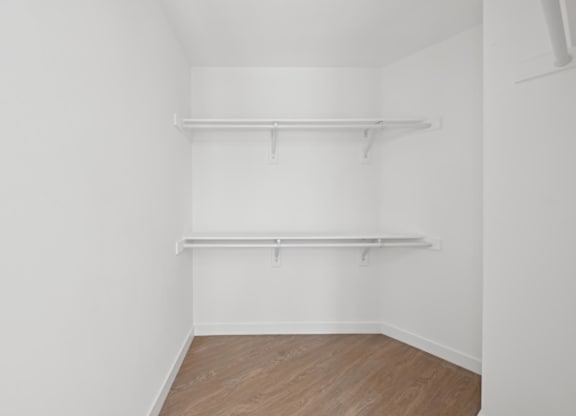 A white room with two shelves and wooden flooring.