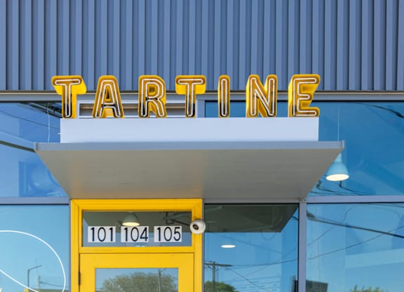 A yellow door with a sign above it that says Tartine.