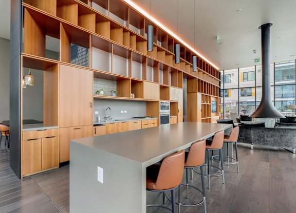 A modern kitchen with a long island and chairs.at Channel House, Oakland, CA 94607