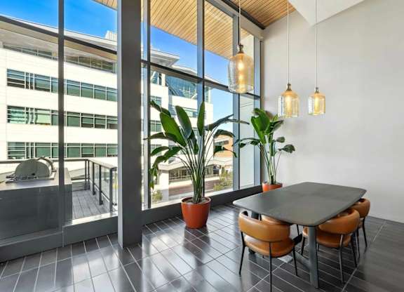 A modern dining area with a table, chairs, and potted plants.at Channel House, Oakland, CA