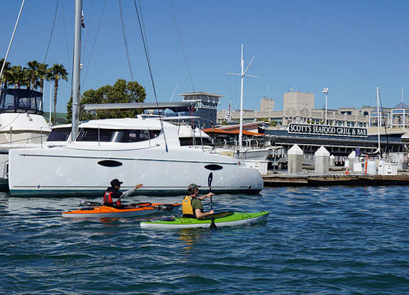 Two people kayaking in the water near a dock.at Channel House, Oakland