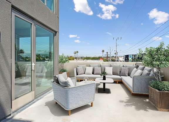 A patio with a couch, chairs, and a table at Coro Apartments, Los Angeles, 90016