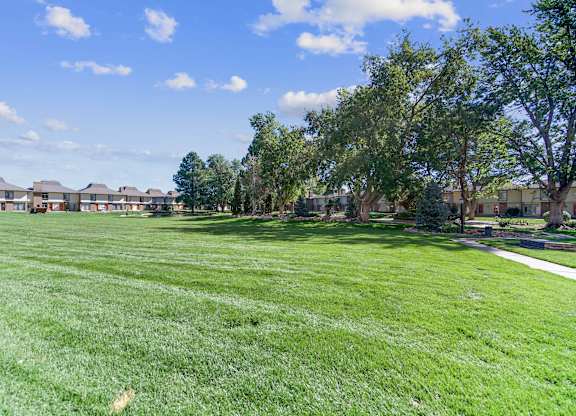 A grassy field with trees and houses in the background. at The Lex At Lowry, Denver, 80224