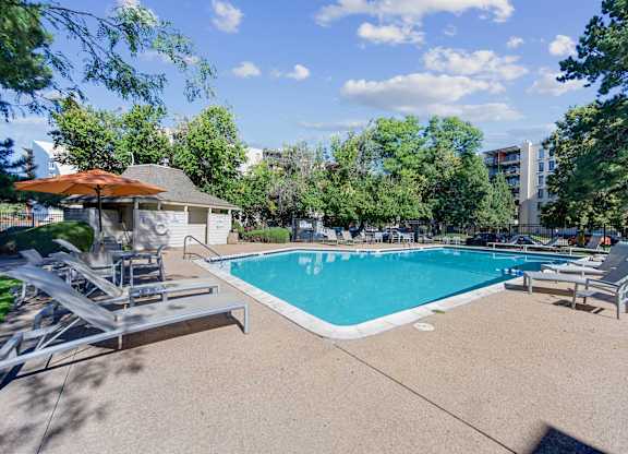 A swimming pool surrounded by trees and a building in the background. at The Lex At Lowry, Denver, Colorado