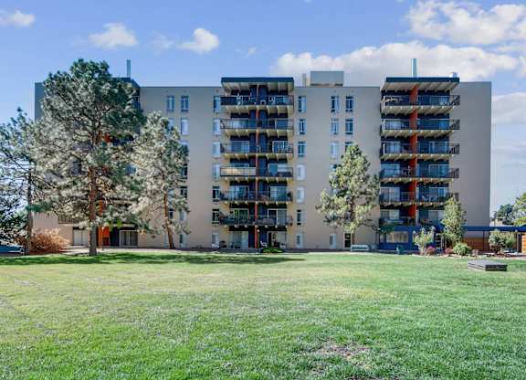 A large apartment building with balconies and a green lawn in front. at The Lex At Lowry, Denver, Colorado