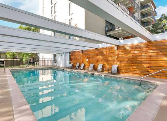 A large indoor swimming pool with a wooden wall and lounge chairs. at The Lex At Lowry, Denver, Colorado