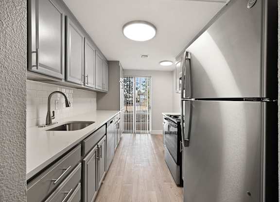 A modern kitchen with stainless steel appliances and wooden floors. at The Lex At Lowry, Denver, CO