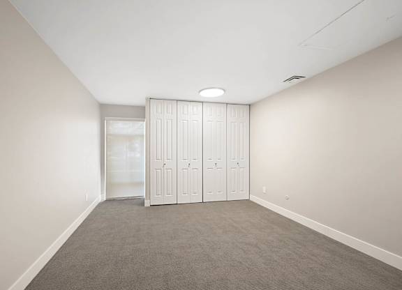 A room with a grey carpet and a white wardrobe. at The Lex At Lowry, Denver, Colorado