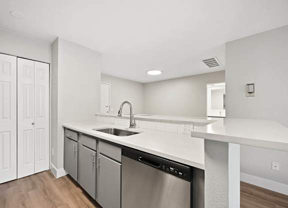 A modern kitchen with white cabinets and a stainless steel dishwasher. at The Lex At Lowry, Denver, Colorado