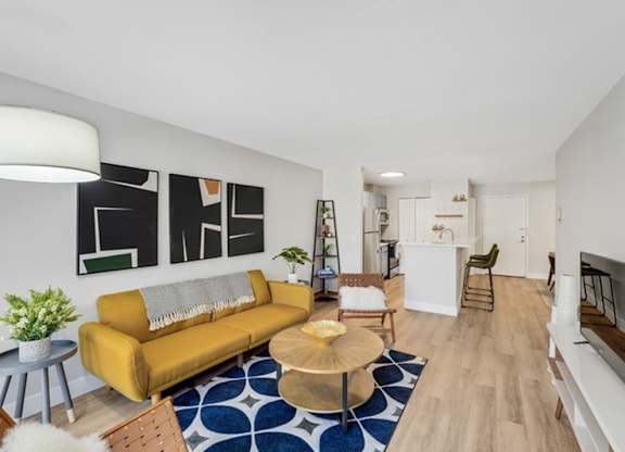 A living room with a yellow couch and a blue and white rug. at The Lex At Lowry, Denver, CO