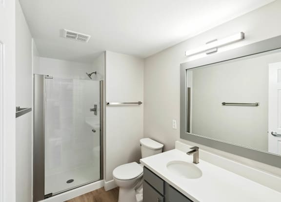 A white bathroom with a toilet, sink, and shower. at The Lex At Lowry, Denver, 80224