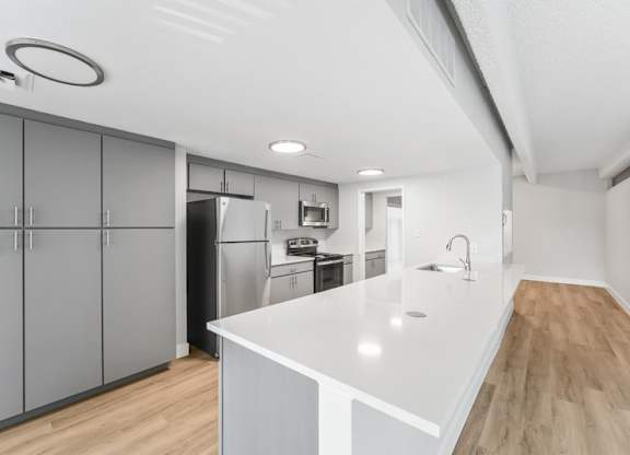 A modern kitchen with a white countertop and wooden flooring. at The Lex At Lowry, Denver, Colorado