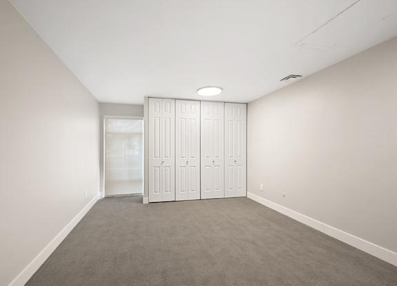 A room with a grey carpet and white walls with a white wardrobe. at The Lex At Lowry, Denver
