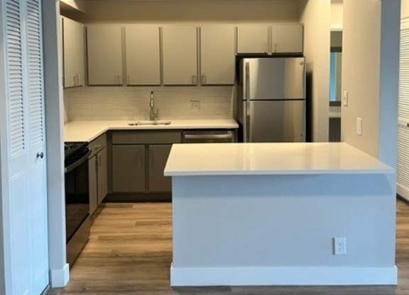 A kitchen with a white countertop and wooden floors. at The Lex At Lowry, Denver