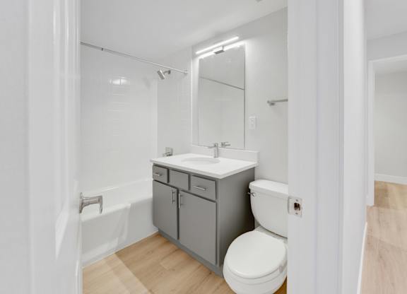 A white toilet sits next to a sink in a small bathroom. at The Lex At Lowry, Colorado