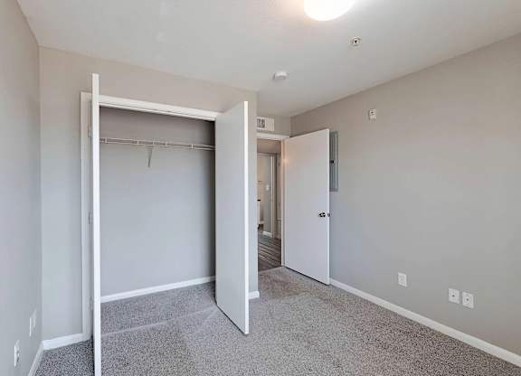 A room with a white door and a grey carpet.