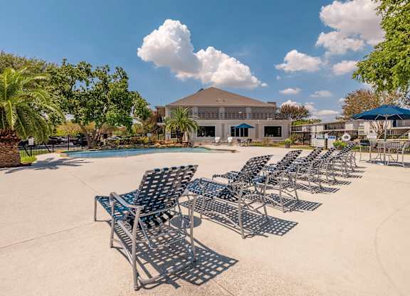 A row of metal chairs are lined up on a concrete surface.