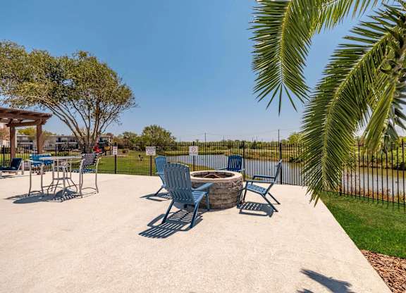 A concrete patio with blue chairs and a table.