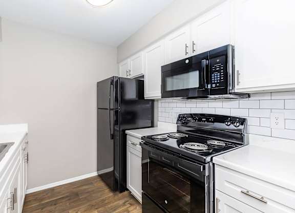 Updated kitchen with black appliances and white cabinetry at Park at LeBlanc Apartments, Fort Worth