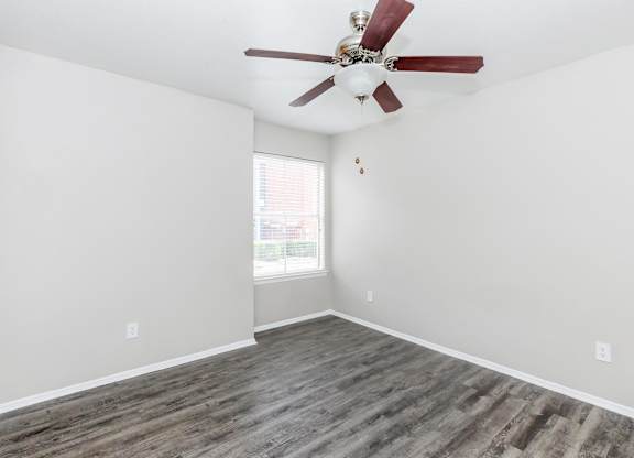 Empty bedroom with ceiling fan and window at Park at LeBlanc Apartments, Fort Worth, Texas