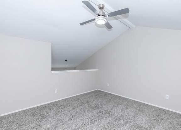 Empty carpeted room with vaulted ceiling and fan at Park at LeBlanc Apartments, Texas