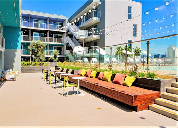 A patio with a long bench and tables is surrounded by buildings.at Prizma, California, 90038