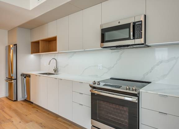 A modern kitchen with a stainless steel refrigerator, microwave, and oven.at Prizma, California  