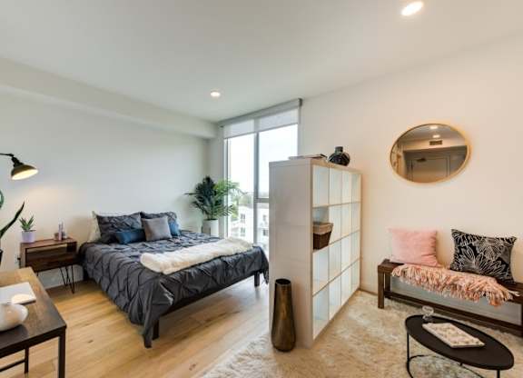 A bedroom with a bed, a bench, and a mirror on the wall.at Prizma, California, 90038