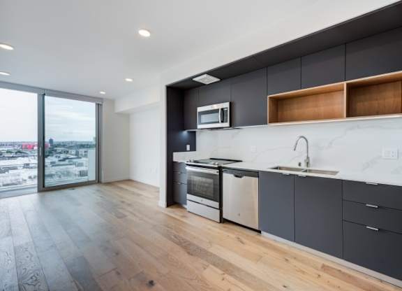 A modern kitchen with a large window overlooking a cityscape.at Prizma, Los Angeles, 90038  